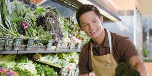 Un vendeur au rayon fruits et légumes qui conseille une cliente